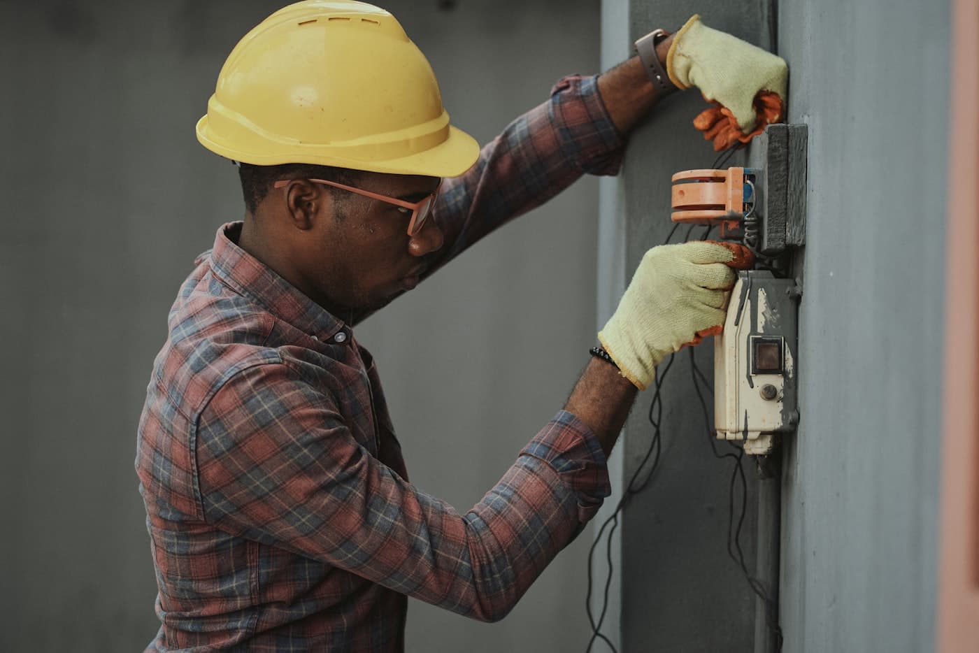 Maintenance technician in a hard hat working on facility equipment