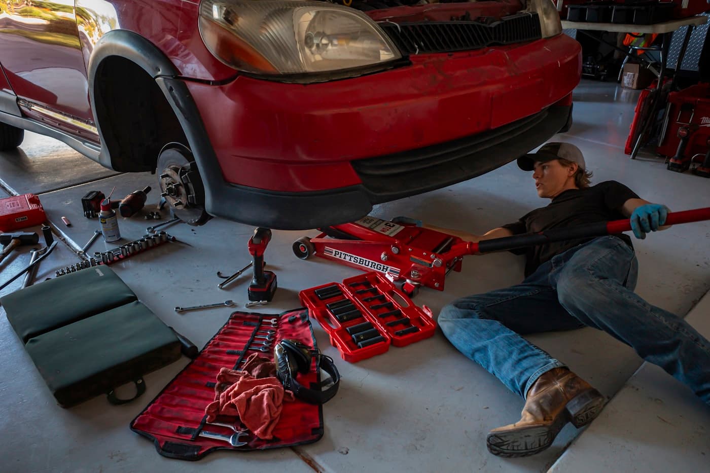 Mechanic completing a work order under a vehicle on a trolley jack
