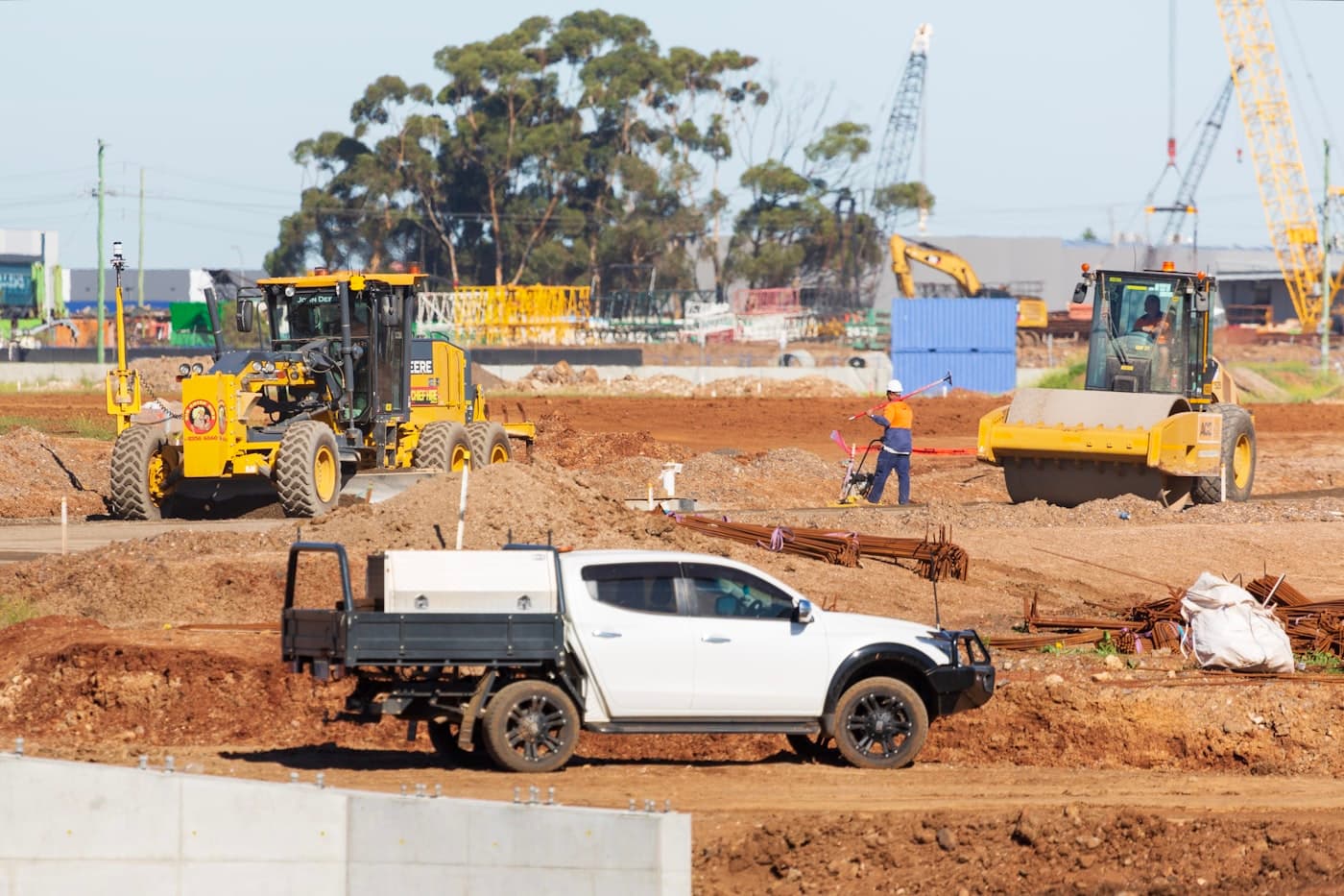 Grader, roller, and site ute working on an Australian construction site